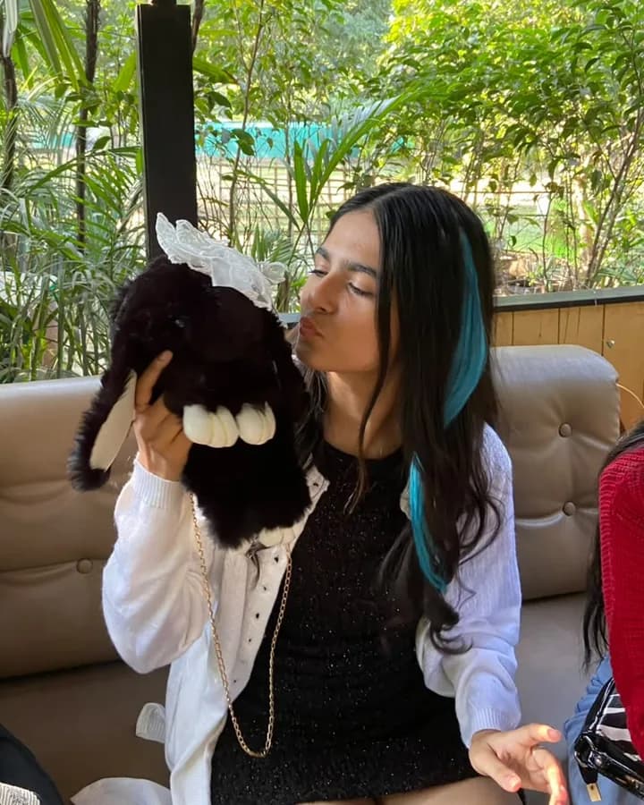 Himanshi in a white jacket, kissing a plush toy