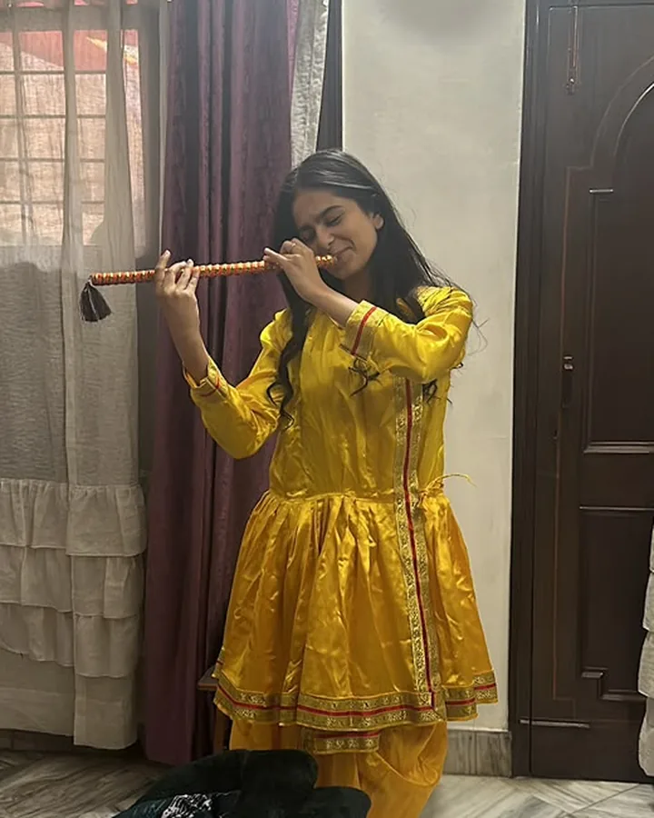 Himanshi in a yellow suit, playing the flute